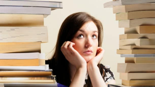 student surrounded by tall stack of books