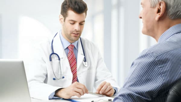 Doctor looking at chart while talking to patient