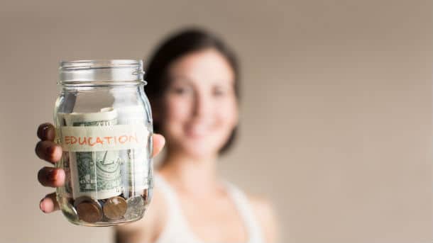 Woman holding up jar filled with money saved for education