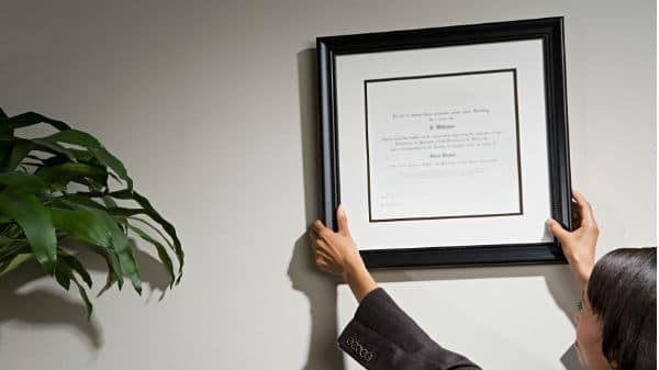 Woman Hanging Certification on the Wall